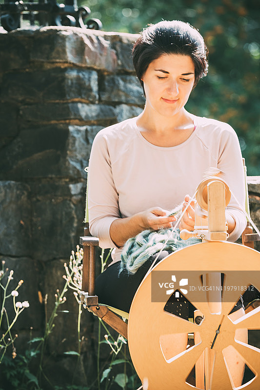年轻女人使用纺车纺羊毛图片素材