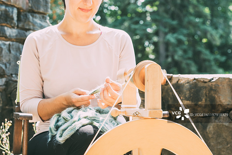 年轻女人使用纺车纺羊毛图片素材