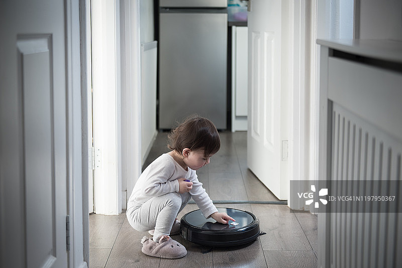 孩子打开走廊里的扫地机器人图片素材