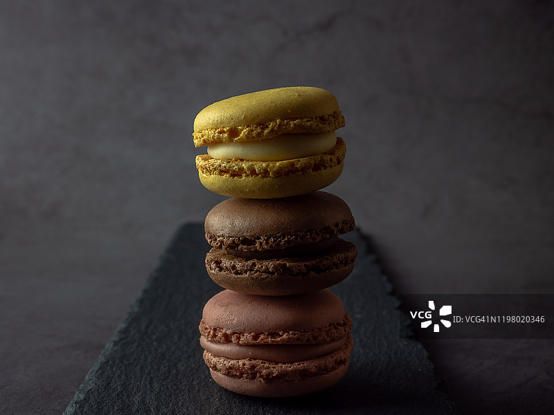 石板盘上、深灰色背景前的马卡龙塔图片素材