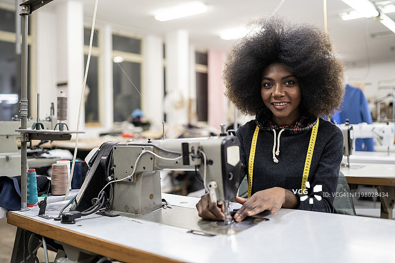 在时装工厂使用缝纫机的非洲工人图片素材