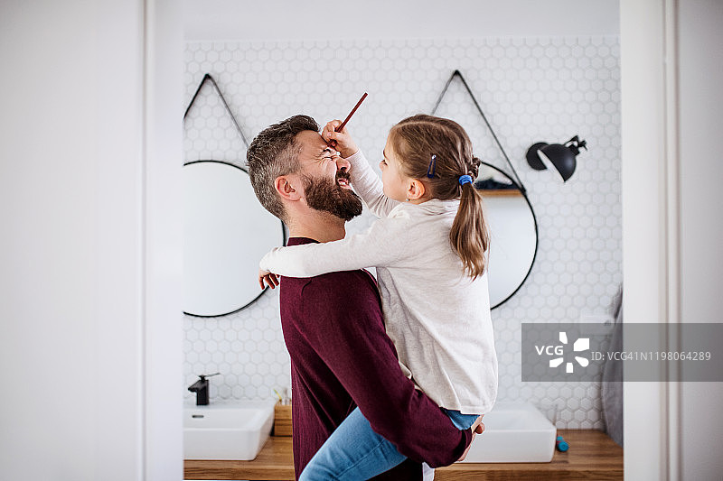 年轻父亲和幼儿女儿在室内浴室玩耍图片素材