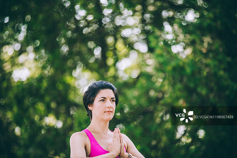 在夏天公园里练习瑜伽的年轻健康棕发女子图片素材