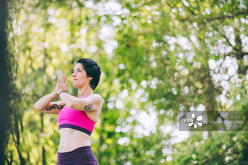 在夏天公园里练习瑜伽的年轻健康棕发女子图片素材