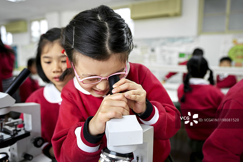 在学校实验室使用显微镜的女学生图片素材