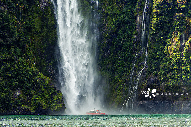 夏季午后，在米尔福德峡湾斯特林瀑布底部被淋湿的游船，新西兰南岛图片素材