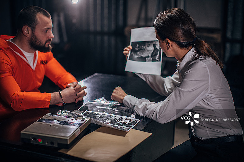 女侦探和男囚犯坐在审讯室里图片素材