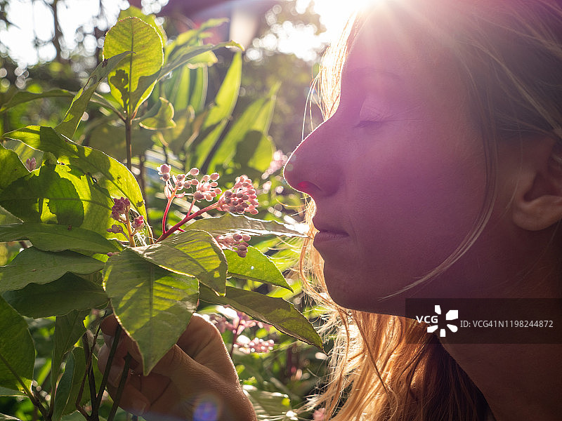 年轻女子在热带花园里闻花香图片素材