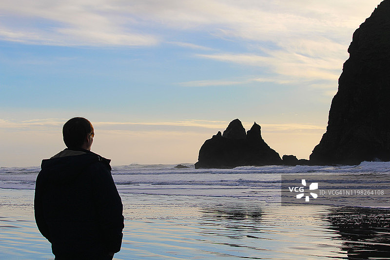 站在海滩干草堆岩石脚下的男人图片素材