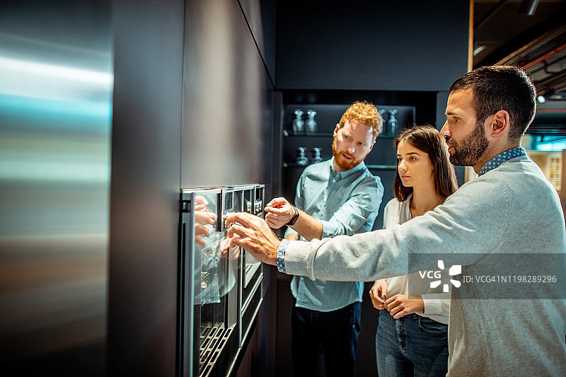 商店售货员向年轻夫妇展示烤箱的功能图片素材