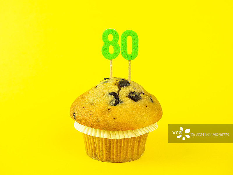 黄色背景上带巧克力碎的80岁生日纸杯蛋糕图片素材