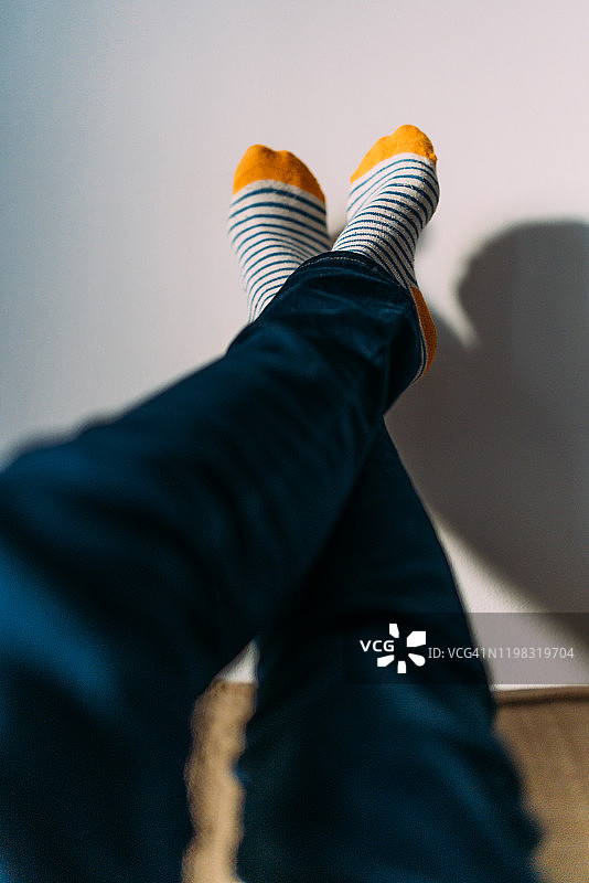 女人在白墙上展示穿着彩色袜子的双脚图片素材