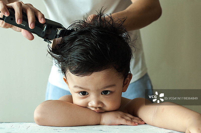 一名亚洲男童在家理发图片素材