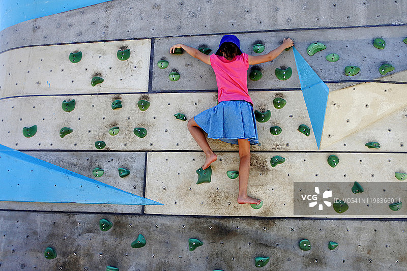 年轻女孩在攀岩墙上攀爬图片素材