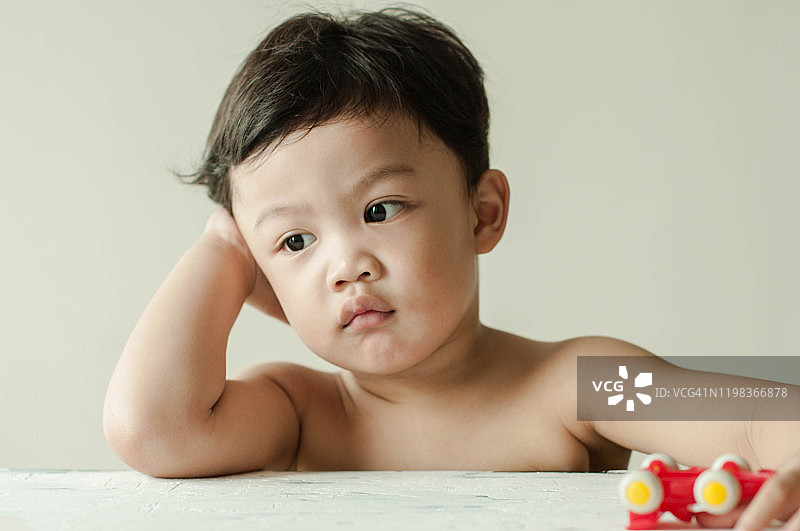 一名百无聊赖的东南亚男童坐在木桌上的肖像图片素材