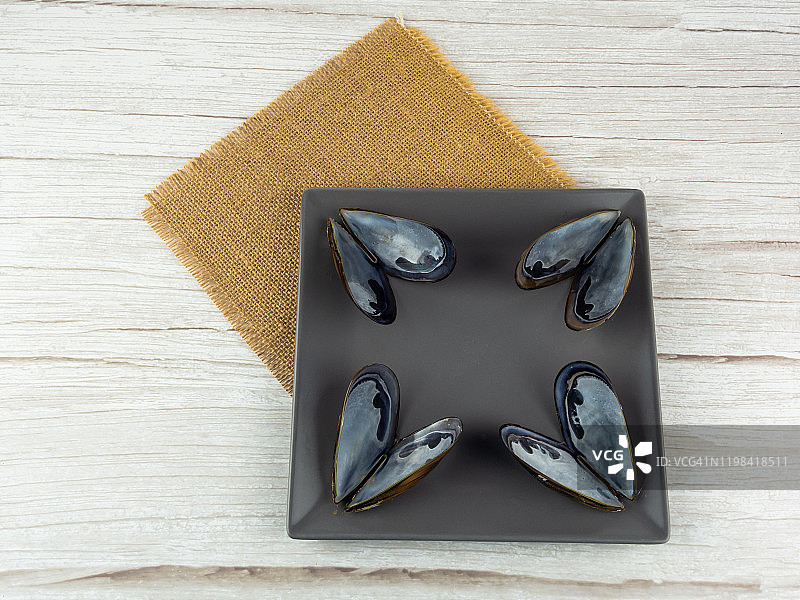 粗麻布上的方形盘子里的贻贝壳图片素材