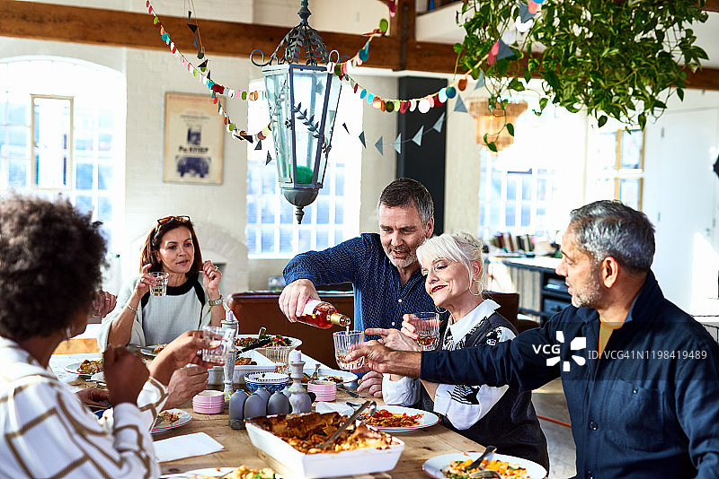 中年男人在餐桌上倒酒图片素材