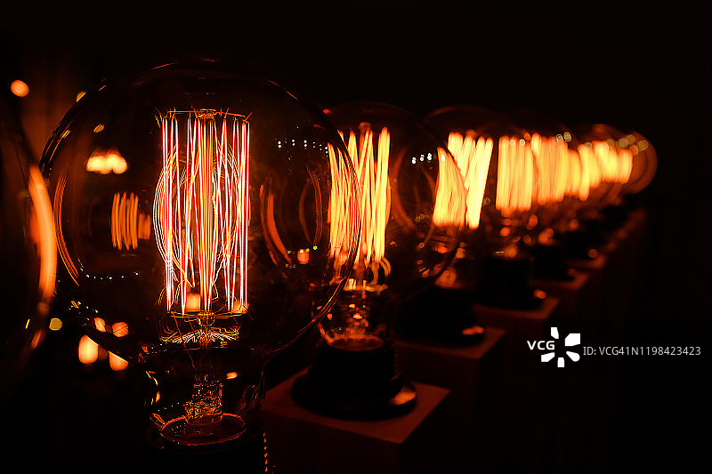 深色背景上的一排复古爱迪生玻璃灯特写，室内设计师灯具，选择性聚焦图片素材