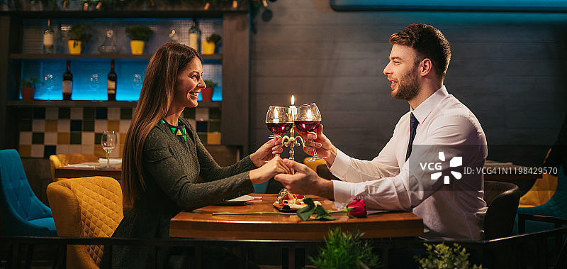 情侣在餐厅浪漫晚餐时手牵手图片素材