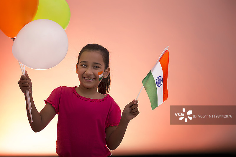 年轻女孩拿着旗帜和气球，独立日图片素材