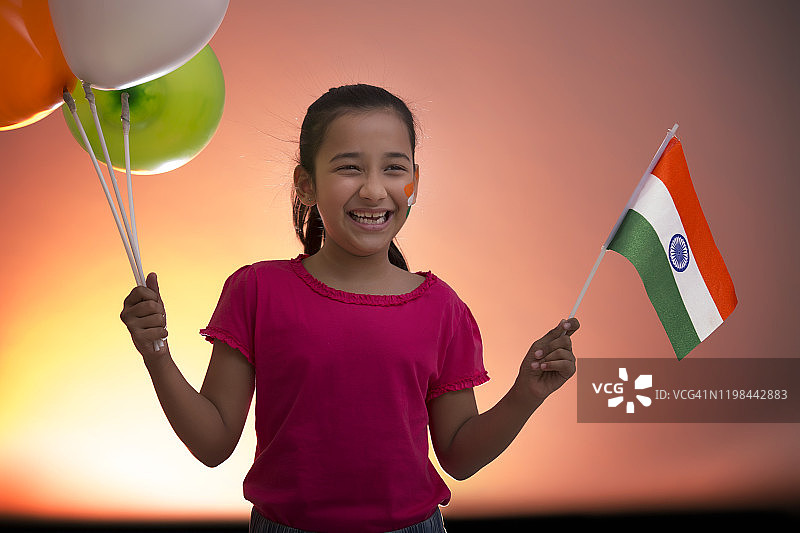 年轻女孩拿着旗帜和气球，独立日图片素材