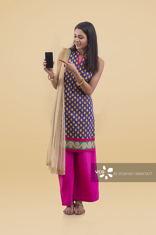 拿着手机并指向它的年轻女人图片素材