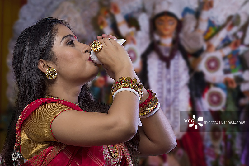 美丽的孟加拉女人在杜尔迦节吹海螺肖像图片素材