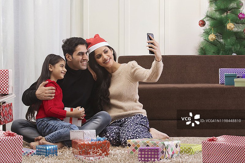 幸福家庭在圣诞节用智能手机自拍图片素材