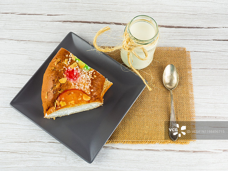 西班牙特色食品。西班牙主显节蛋糕，奶油馅国王面包圈，一杯牛奶和粗麻布上的旧羊驼勺图片素材