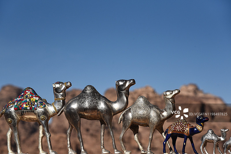 一排单峰骆驼玩具，背景是山脉图片素材