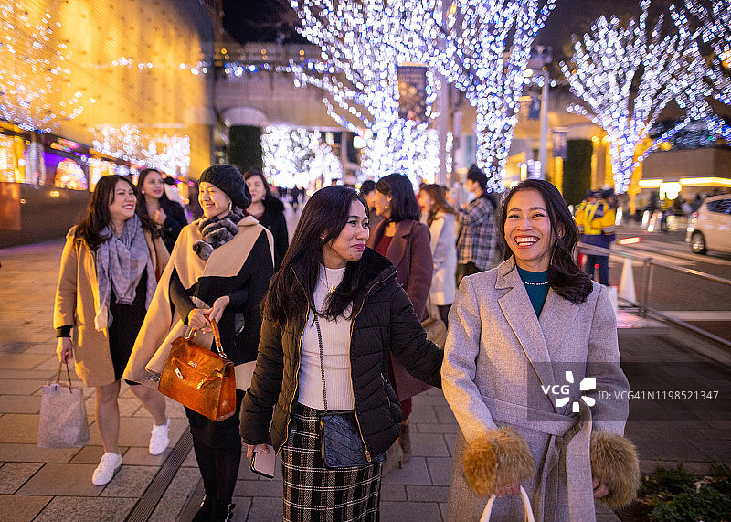 圣诞夜在城市街道上行走的亚洲女性图片素材
