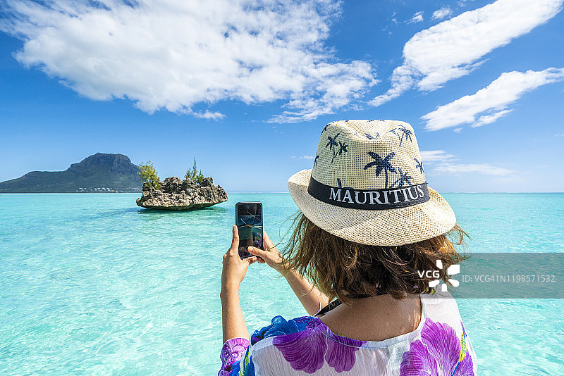 女人用智能手机拍摄毛里求斯热带泻湖和水晶岩图片素材