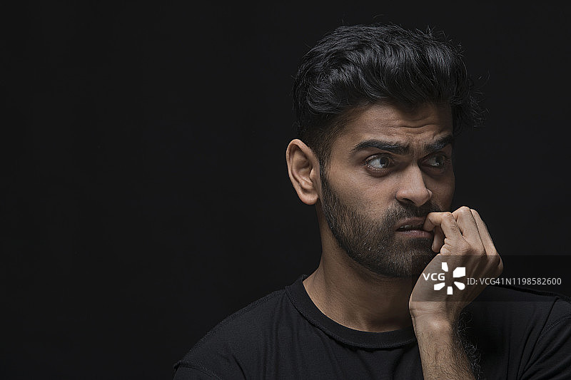 困惑的年轻男人咬指甲图片素材