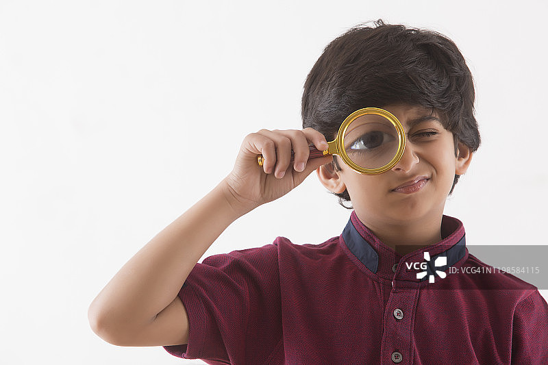 用放大镜观察的年轻男孩肖像图片素材