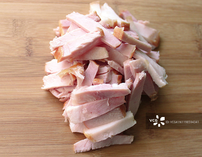 木制背景上切成条的烟熏猪肉火腿图片素材