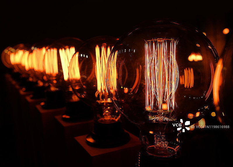深色背景上的一排复古爱迪生玻璃灯特写，室内设计师灯具，选择性聚焦图片素材