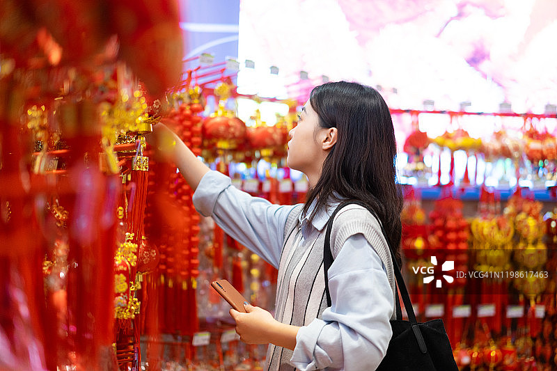 亚洲女性挑选色彩鲜艳的中国新年装饰品图片素材