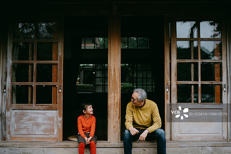 祖父和孙女坐在露台上互相微笑图片素材