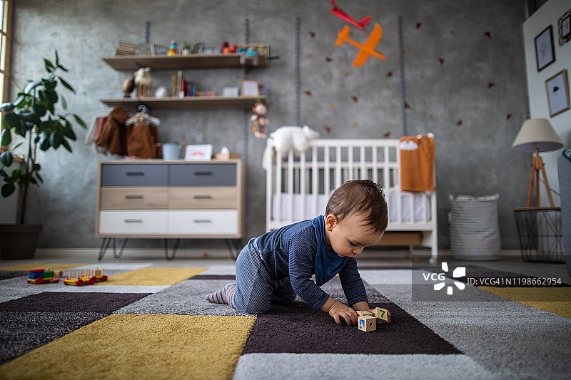男婴在游戏室里爬行玩积木图片素材