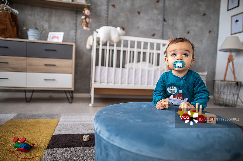 好奇的男婴在游戏室里玩他最喜欢的玩具图片素材