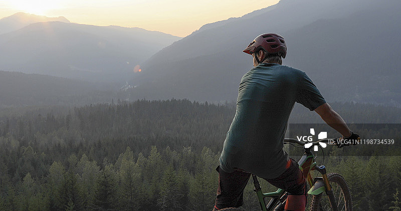 山地自行车手穿越群山和山谷之间的道路图片素材