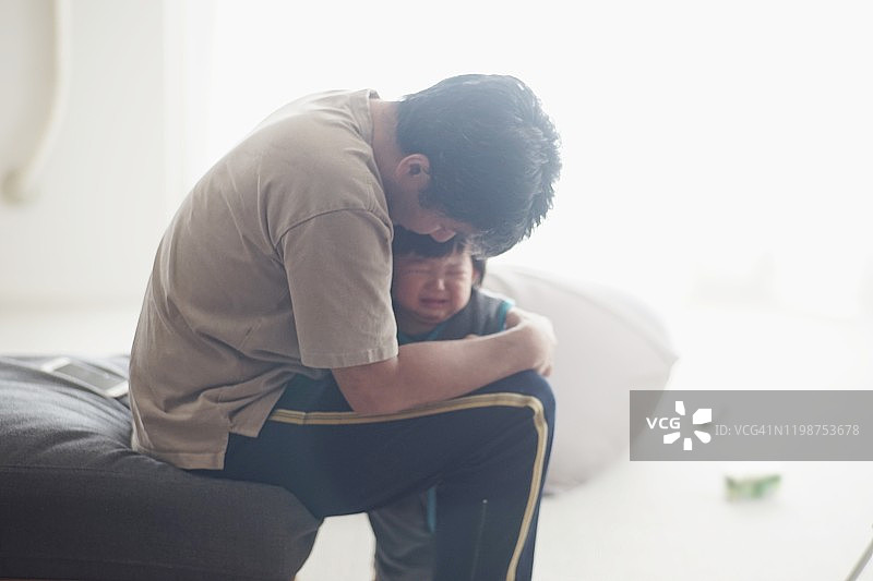 父亲在家抱着哭泣的男婴图片素材