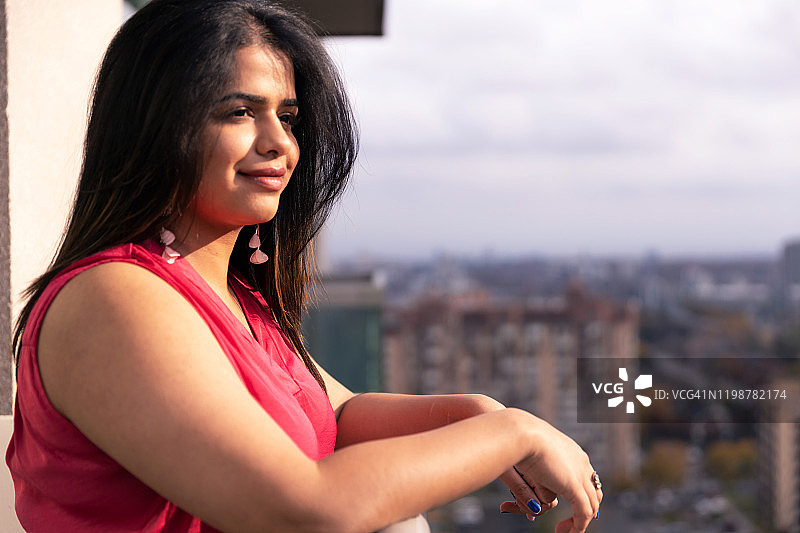 女孩站在阳台上拥抱冬日阳光图片素材