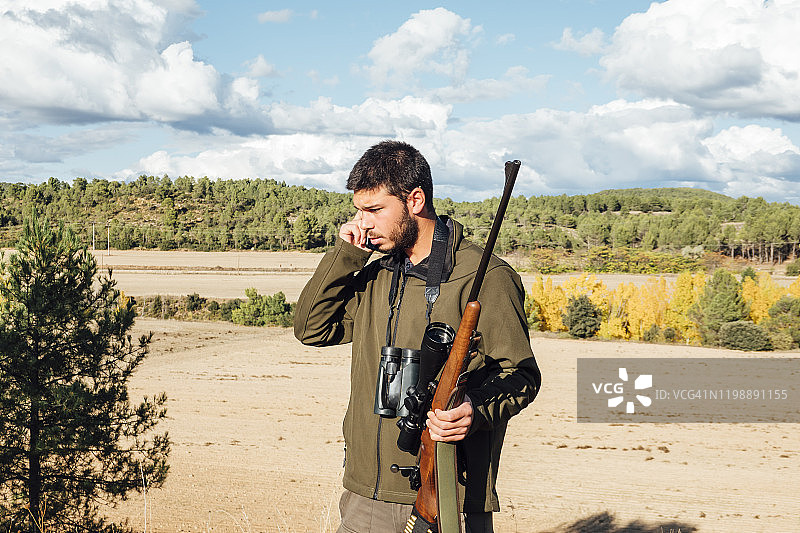 男人在山上用双筒望远镜和步枪使用手机图片素材