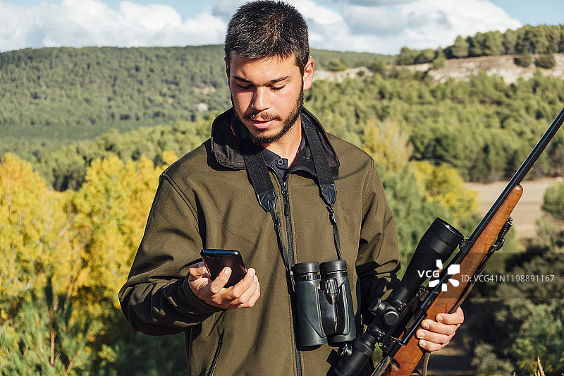 男人在山上用双筒望远镜和步枪使用手机图片素材