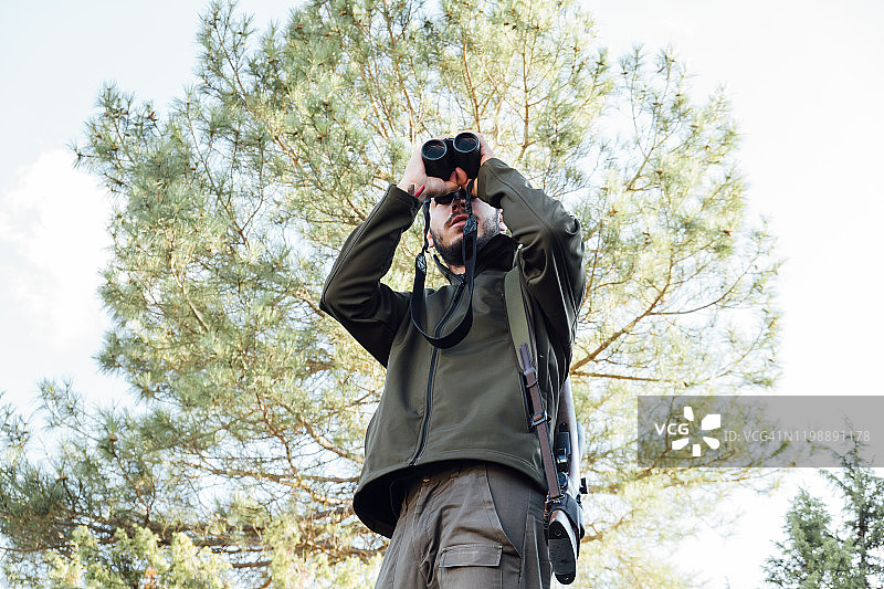 猎人在山上手持望远镜观察图片素材