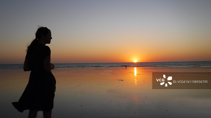 年轻女子观看日落的轮廓图片素材