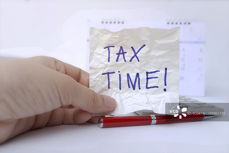 报税季概念：手持写有“报税季”字样的纸条图片素材