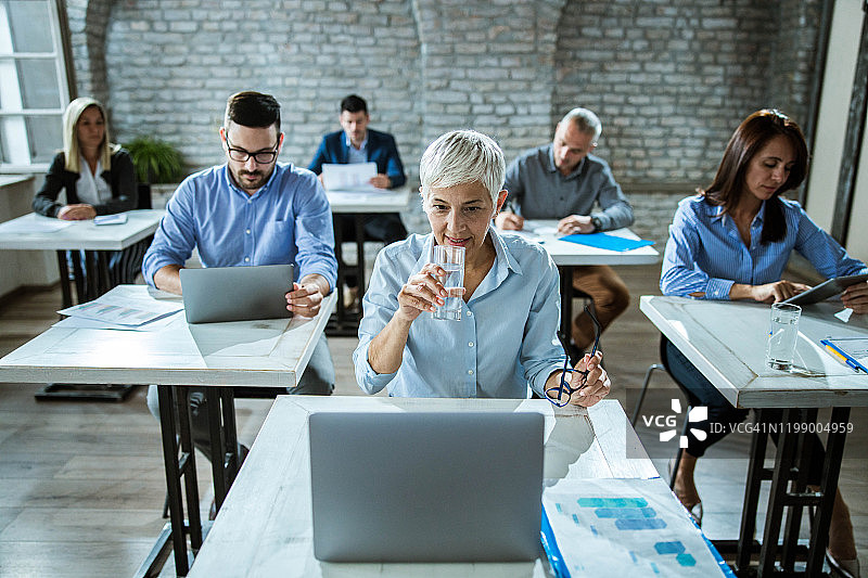 在公司办公室使用笔记本电脑的快乐老年程序员图片素材