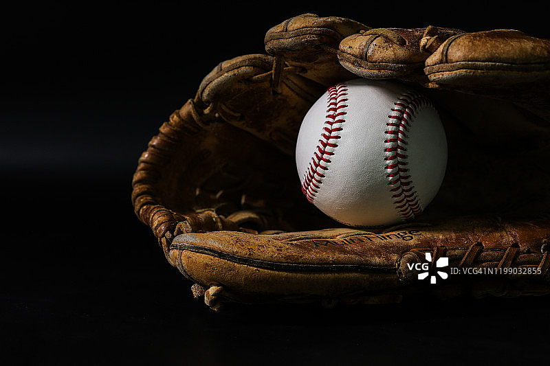 黑色背景上的手套和棒球图片素材
